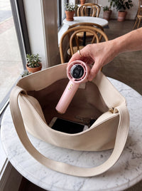 Frostbite fan being lowered into a shoulder bag on a cafe table